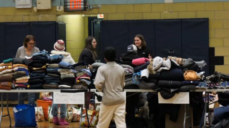 Migrantes van a evento en escuela de distribución de ropa