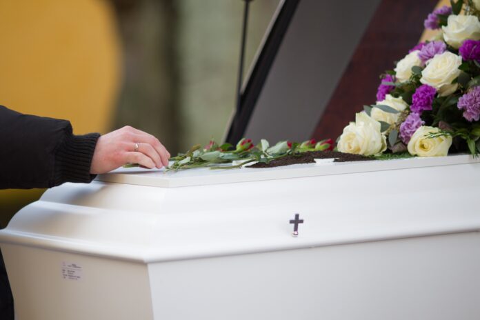 closeup-shot-person-hand-casket-with-blurred-background.jpg