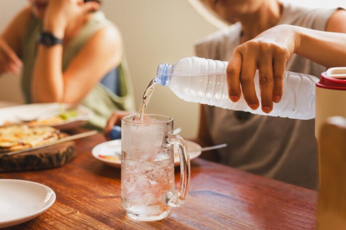 woman-pouring-cold-water-from-bottle-into-glass-dinner-table-1500x1000.jpg